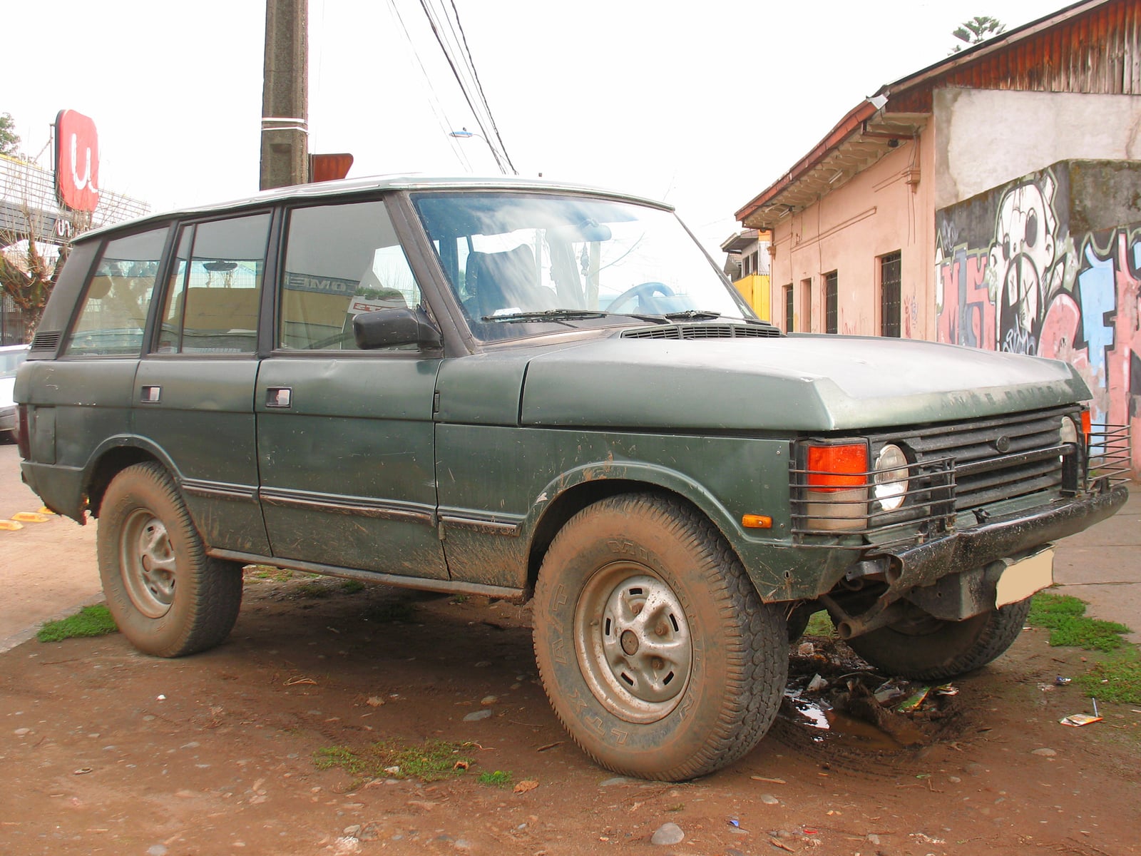 A weathered green Range Rover Classic parked on a street