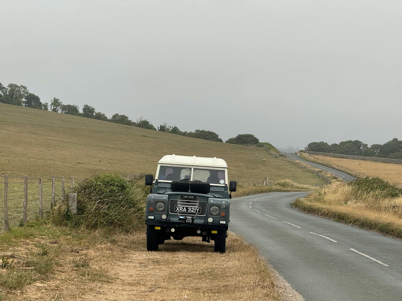 A Land Rover Series III parked on a winding country road
