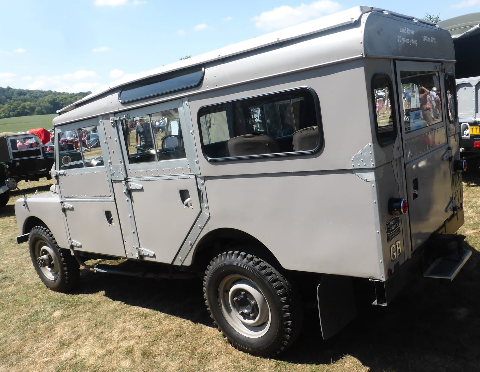 A grey 1956 Land Rover Series I 107 station wagon with a safari roof on a show field