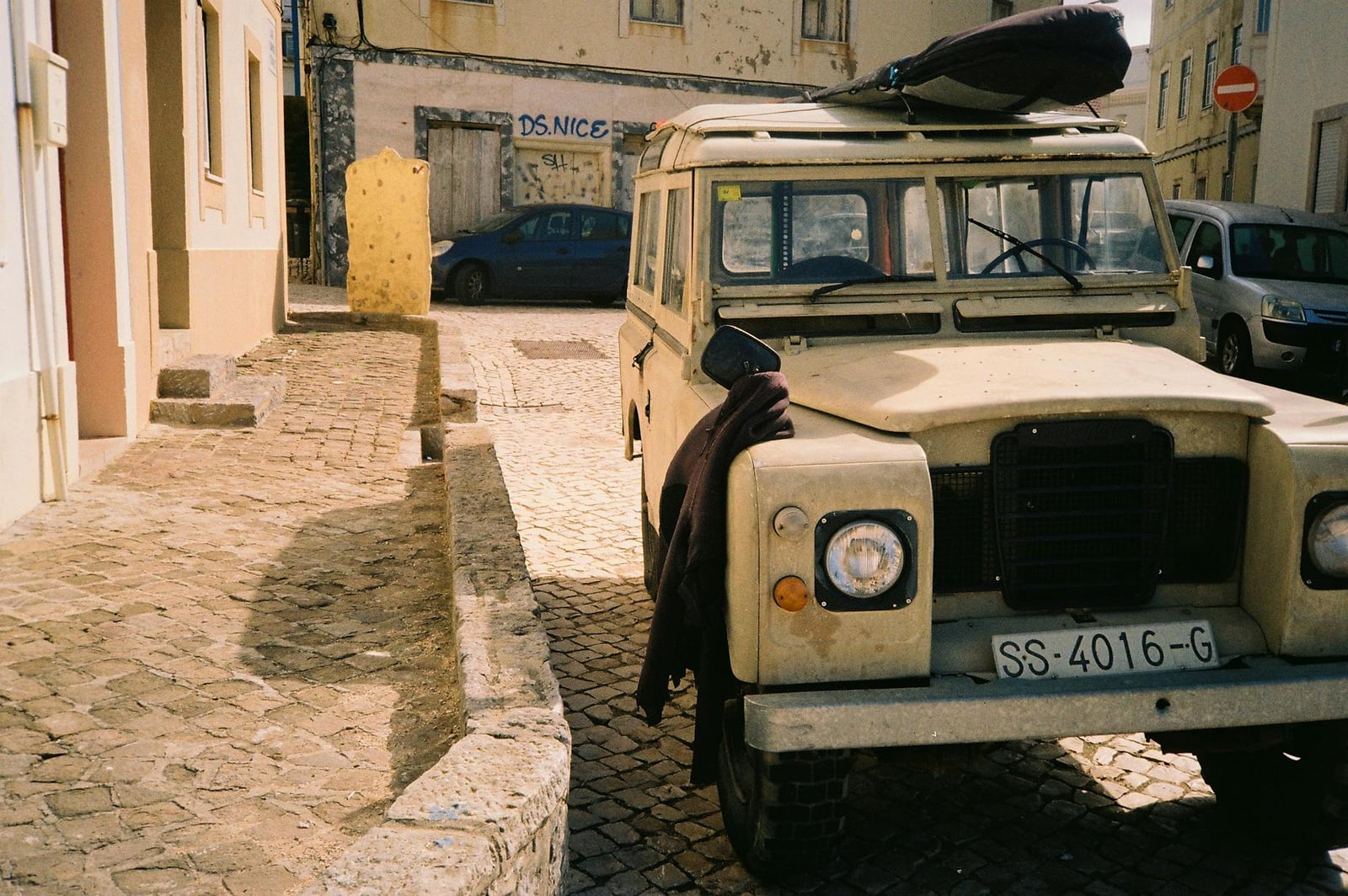 A cream Land Rover Series III station wagon parked on a cobbled street