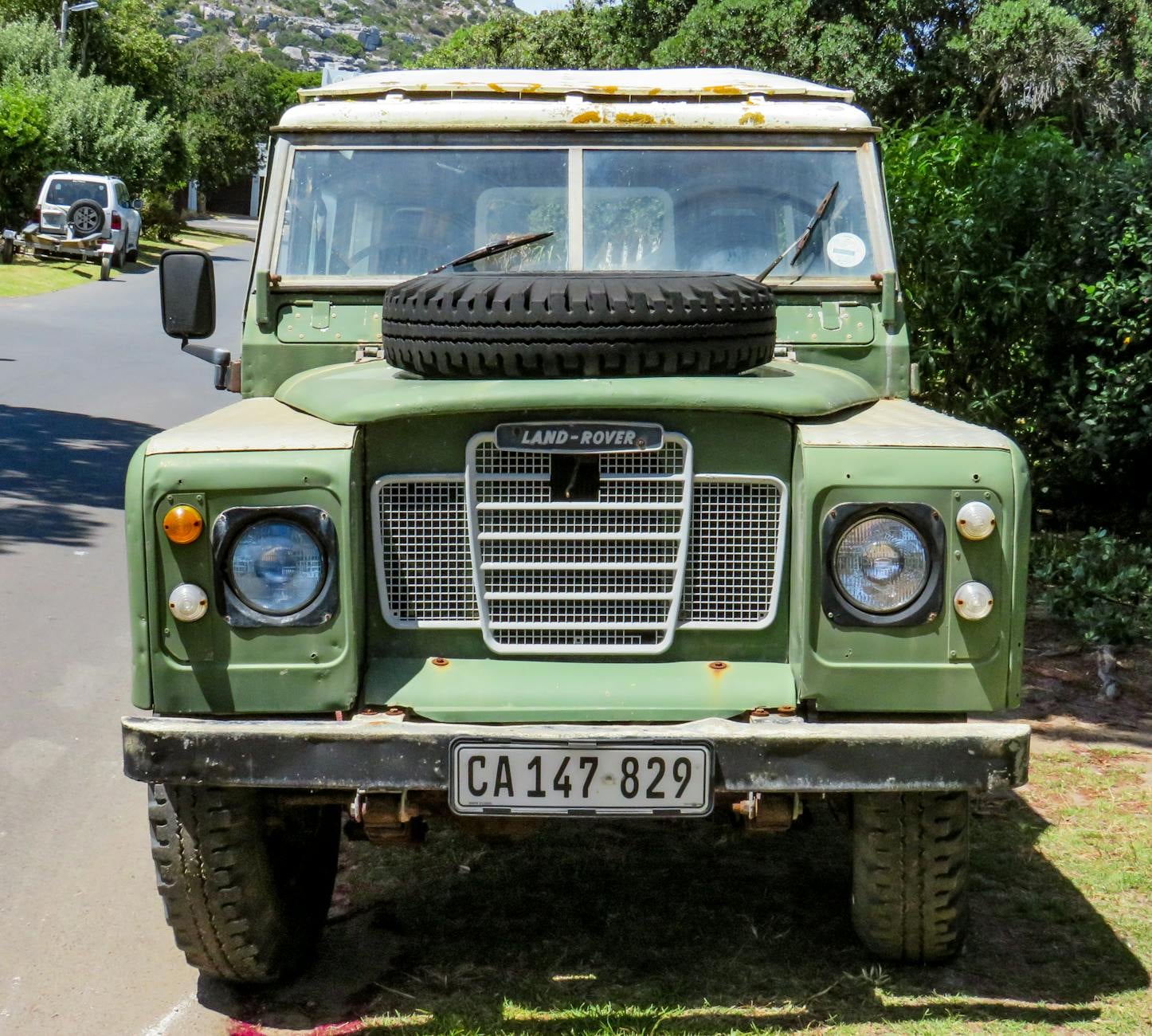 A Bronze Green Land Rover Series with a bonnet-mounted spare wheel