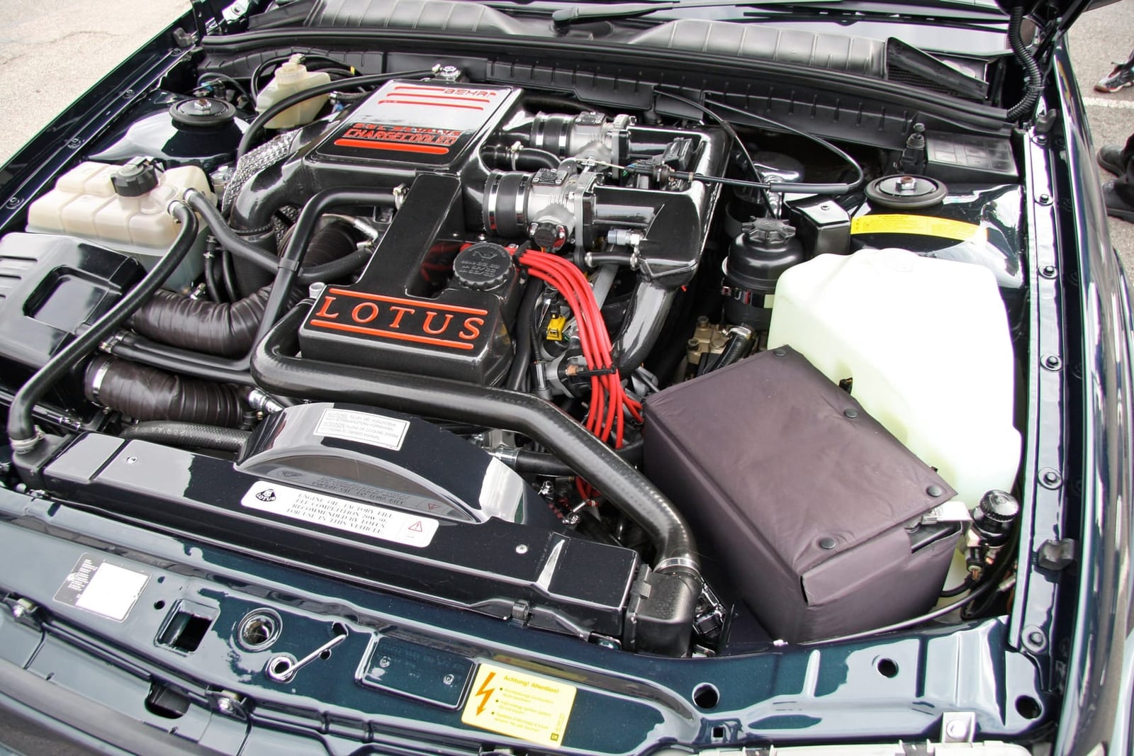 The engine bay of a Lotus Carlton showing the twin turbochargers, intercooler pipework and the Lotus cam cover