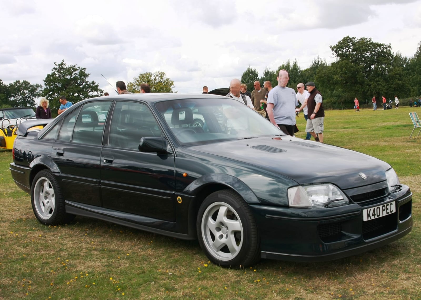A dark green Lotus Carlton on grass at a classic car show, side view, UK registration K40 PEC