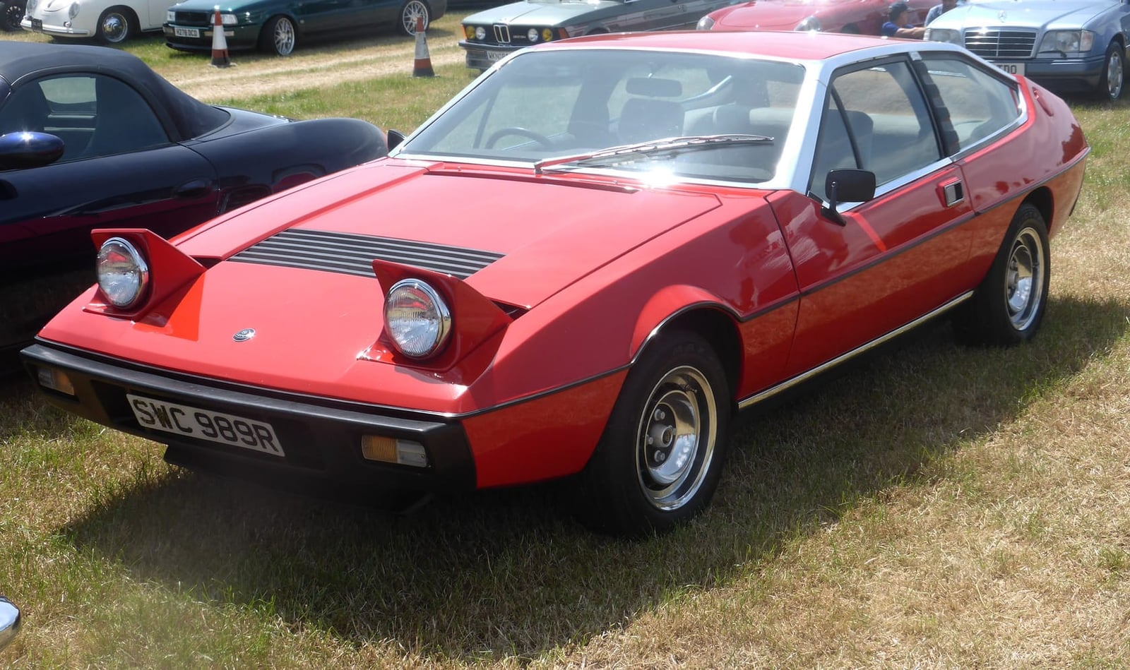A red 1977 Lotus Eclat with pop-up headlamps raised, front three-quarter view, UK registration SWC 989R