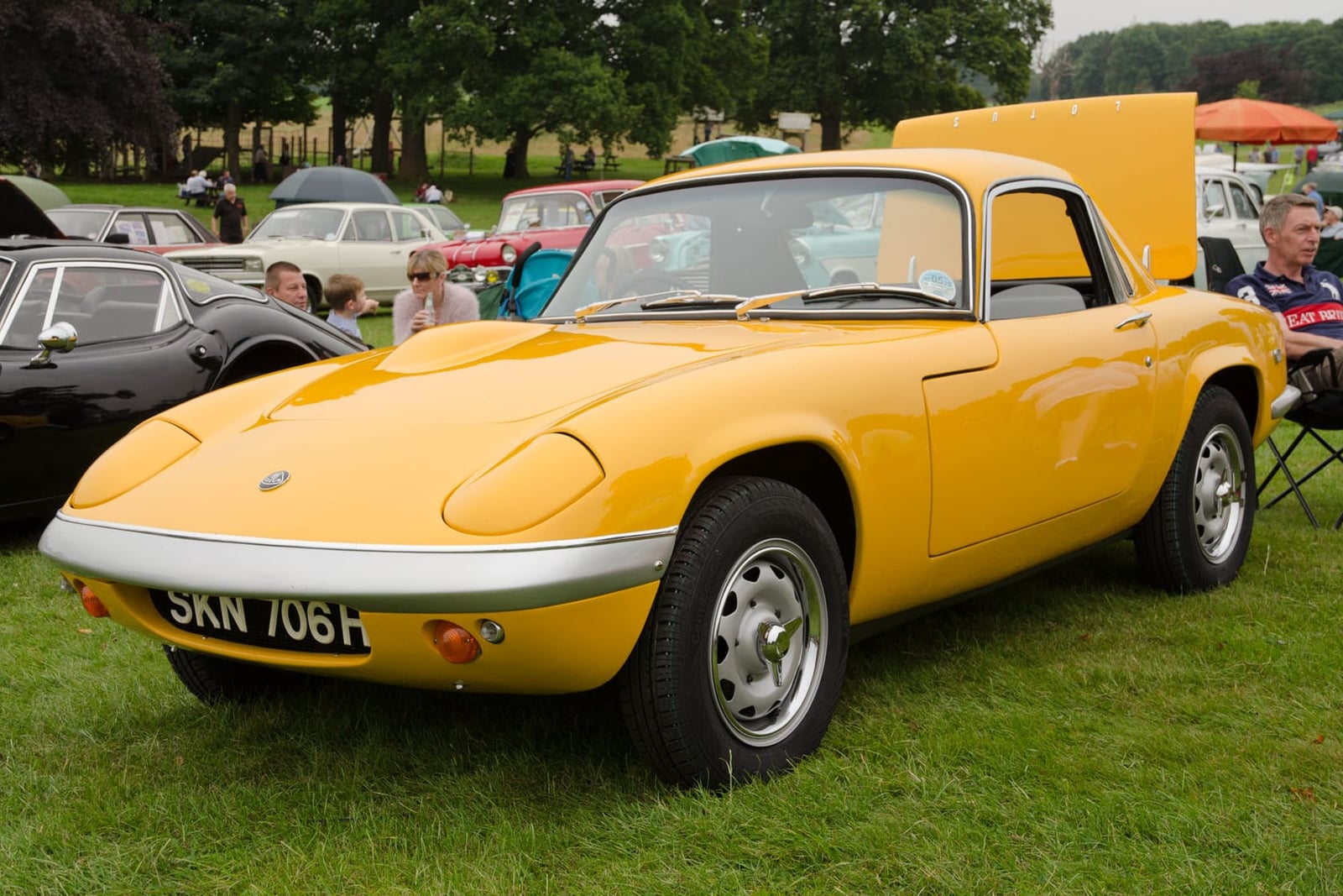 A yellow 1969 Lotus Elan fixed-head coupé with a UK registration on grass at a show
