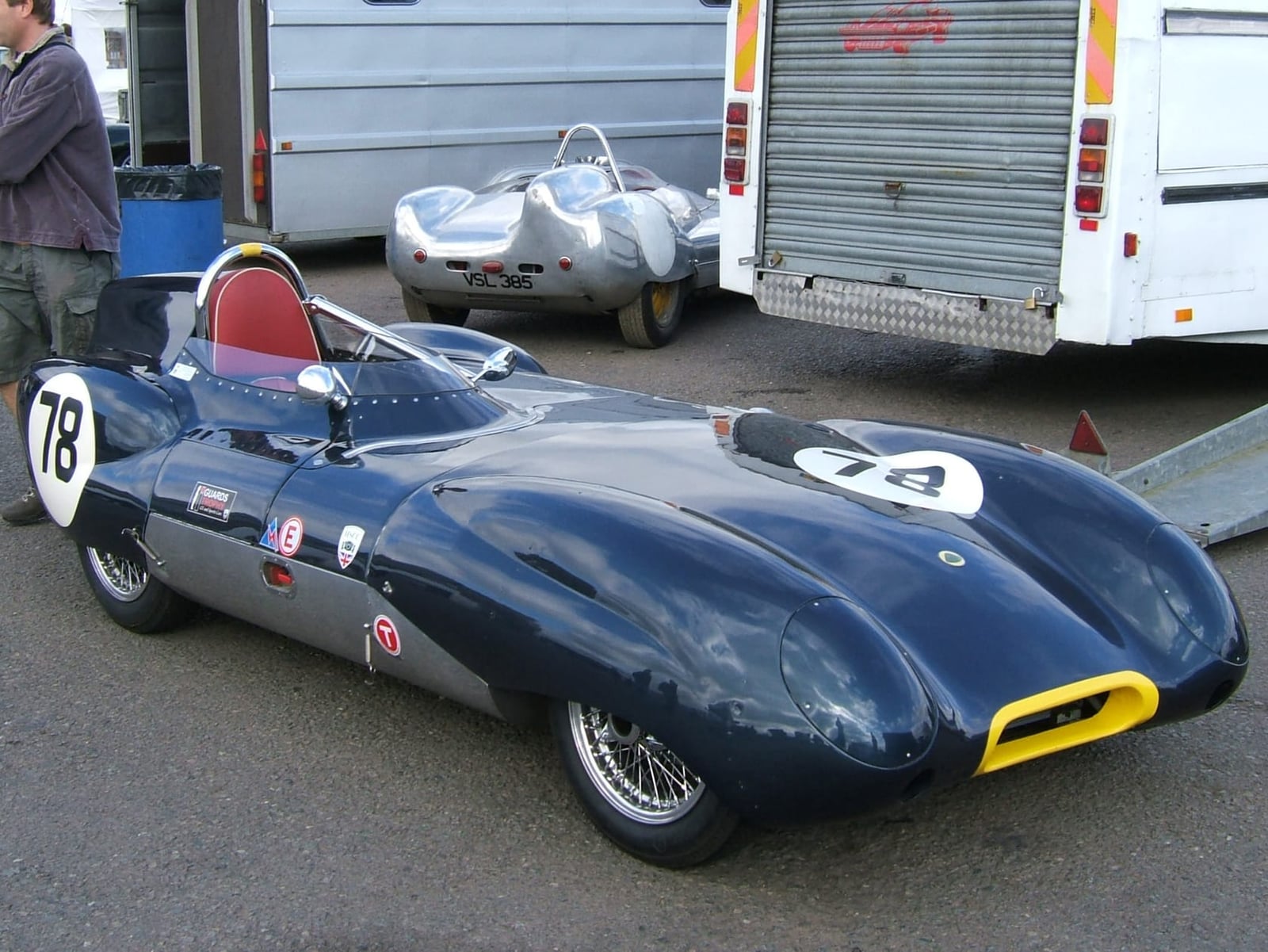 A dark blue Lotus Eleven carrying number 78 beside a Lotus 15 in a paddock