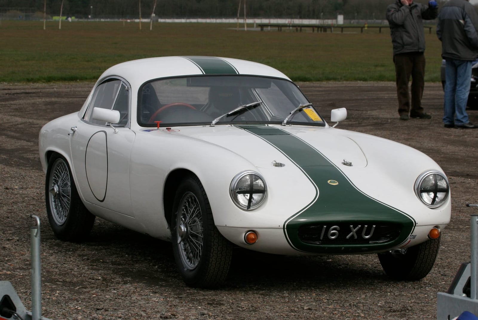 A white and green Lotus Elite competition car in a circuit paddock, side view, UK registration 16 XU