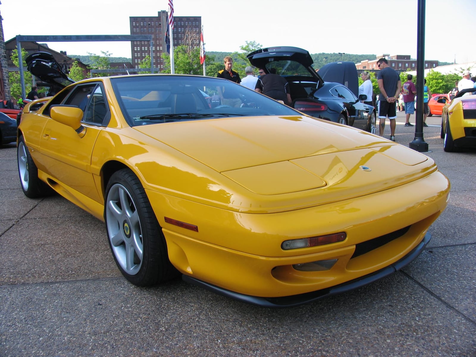 A yellow Lotus Esprit S1 on grass at a classic car show, front three-quarter view, UK registration FYC 762C