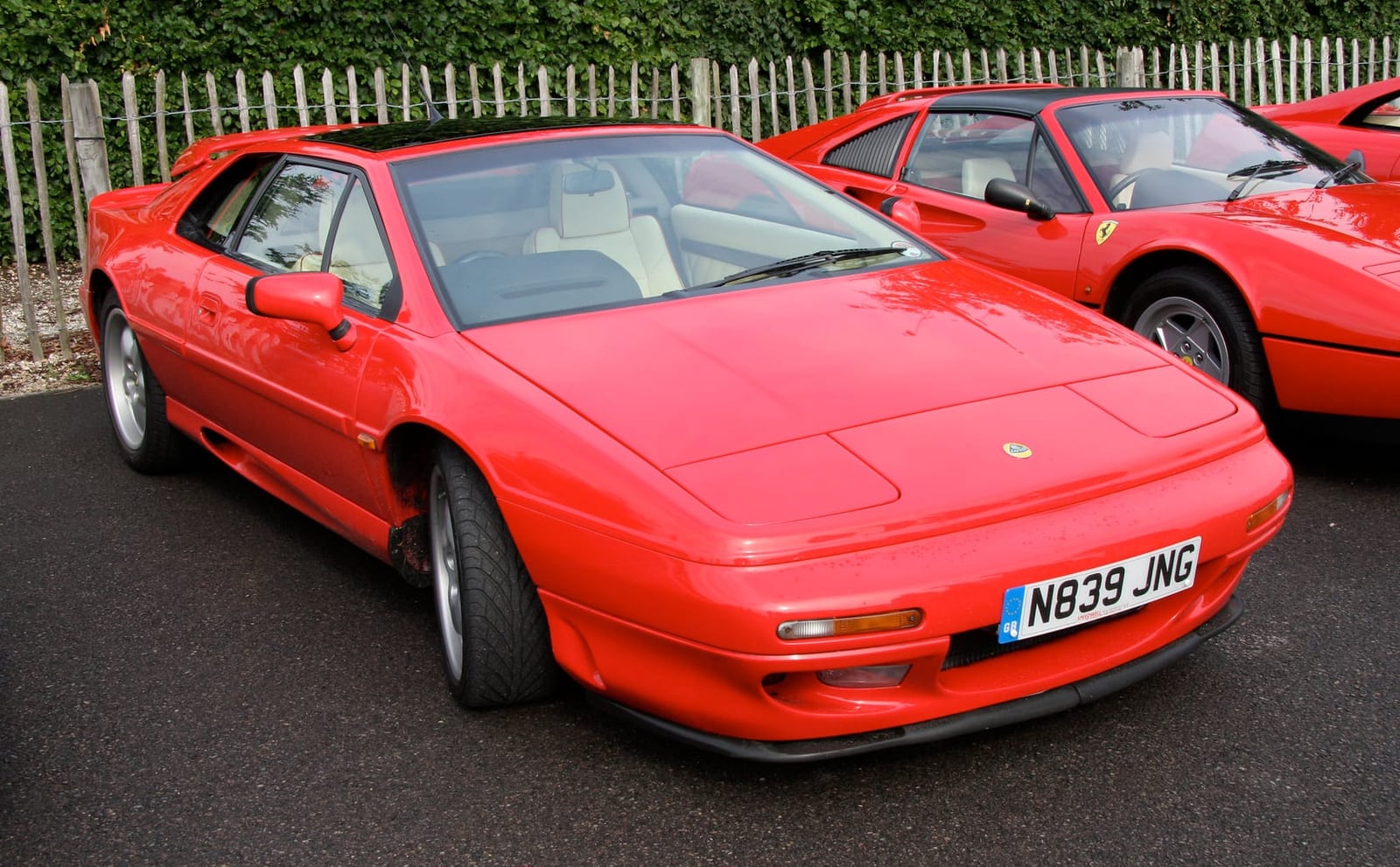 A red Lotus Esprit parked on tarmac at a car event, front three-quarter view, UK registration N839 JNG
