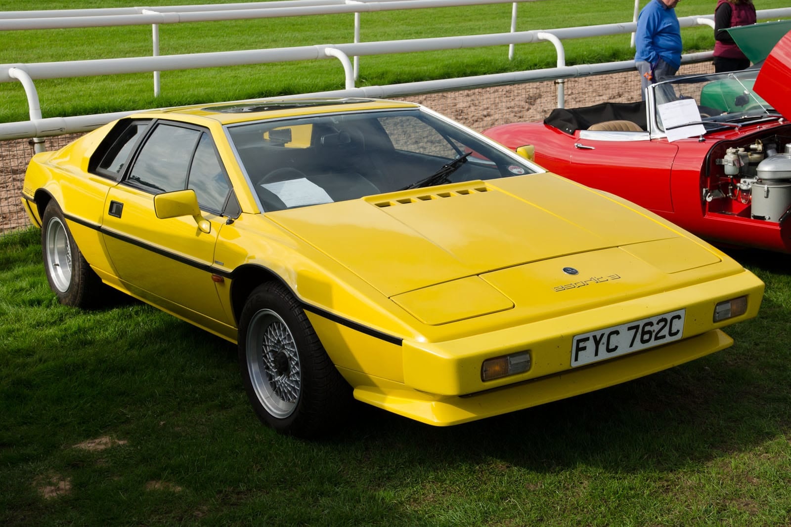 A red 1982 Lotus Esprit S3 on grass at a show, front three-quarter view, UK registration BNG 293T