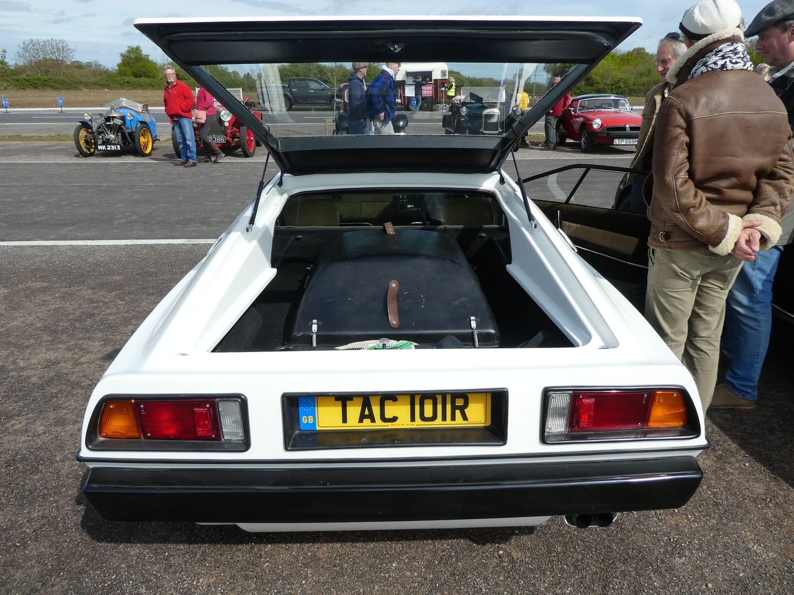 A yellow 1977 Lotus Esprit on grass at a show, front three-quarter view, UK registration FYC 762C