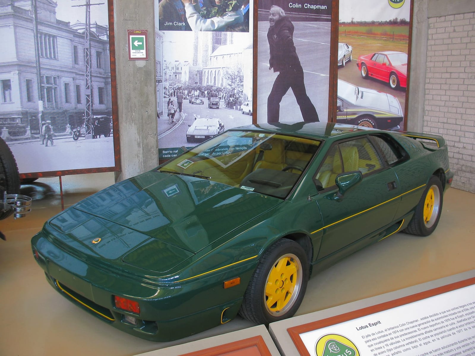 A green and yellow Lotus Esprit SE Jim Clark Edition on museum display beside a photograph of Colin Chapman