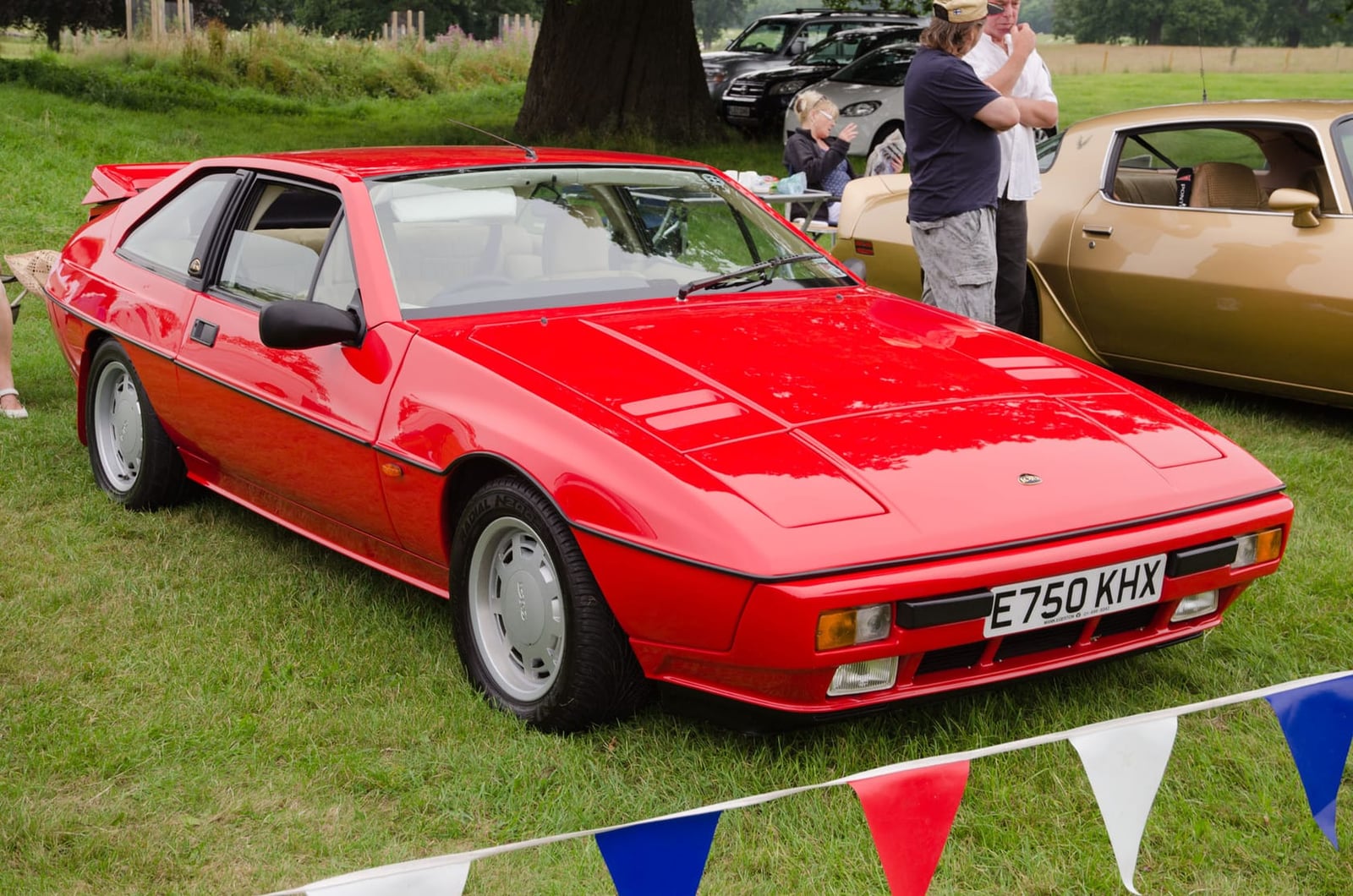 A red 1987 Lotus Excel at a showfield, front three-quarter view, UK registration E750 KHX