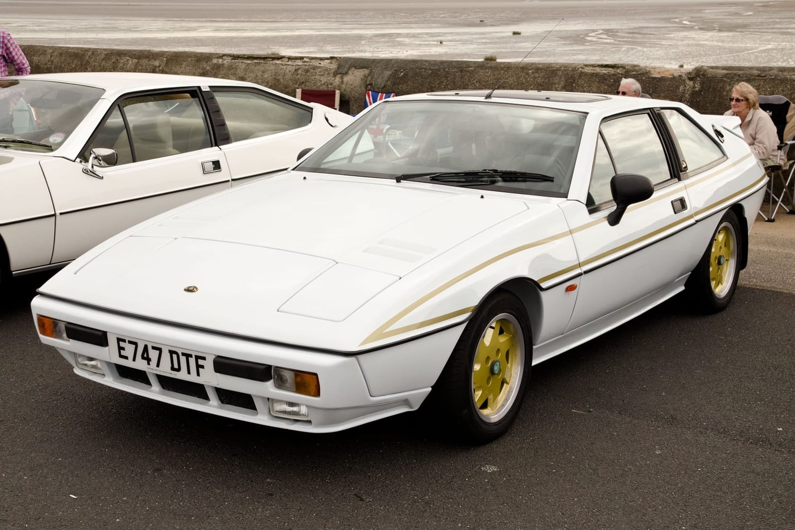 A red Lotus Excel on grass at a classic car show with bunting behind, front three-quarter view, UK registration E750 KHX