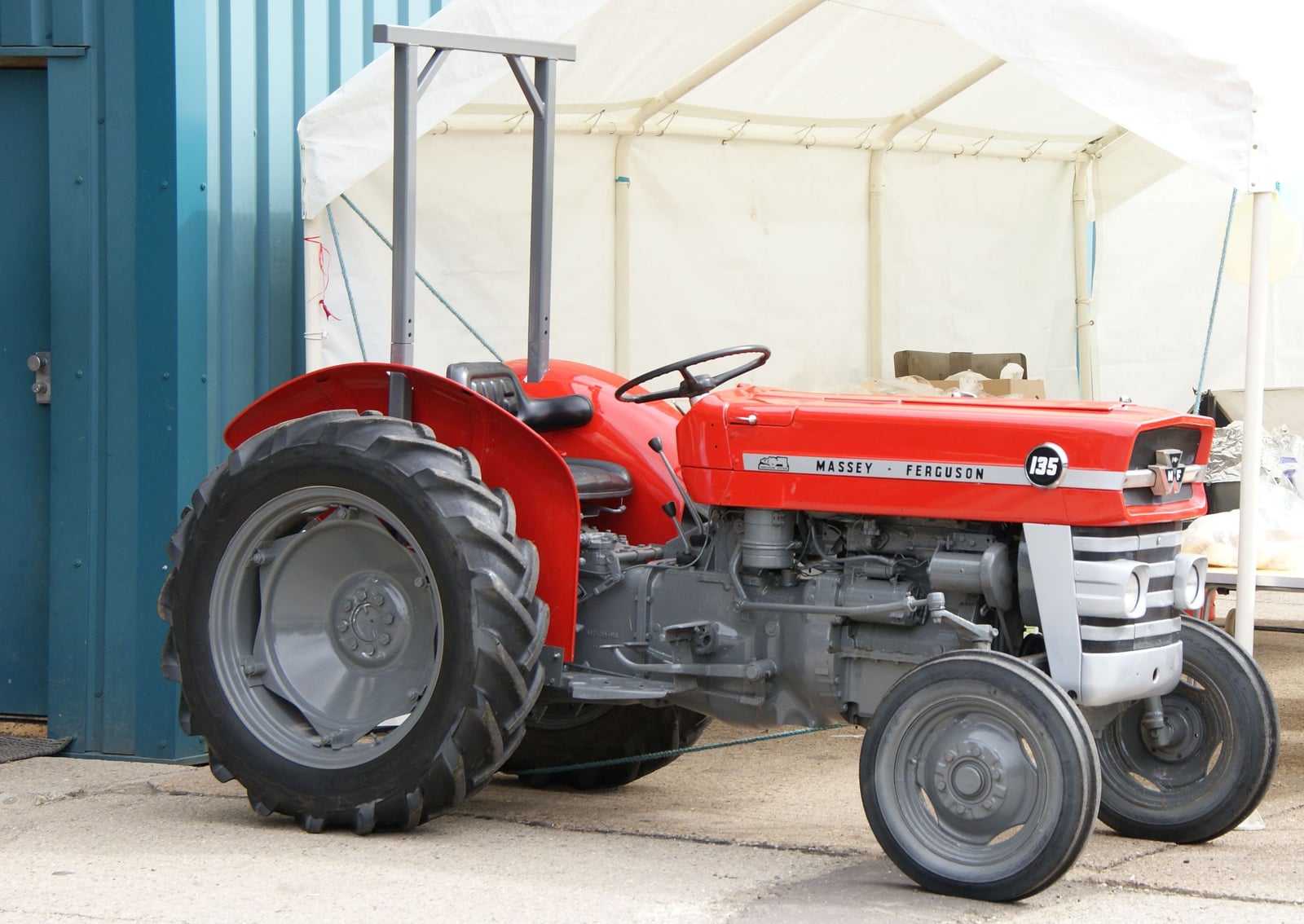 An immaculately restored red Massey Ferguson 135, the 135 badge crisp on the bonnet, displayed under a show marquee