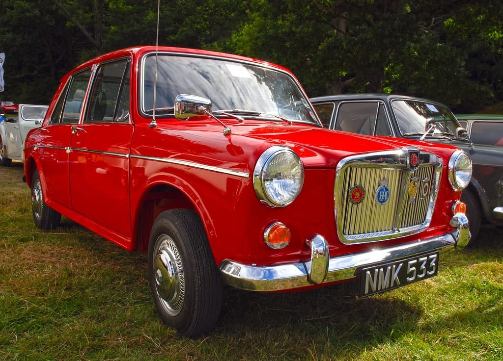 A red MG 1100 on grass at a classic car show, front three-quarter view, UK registration NMK 533