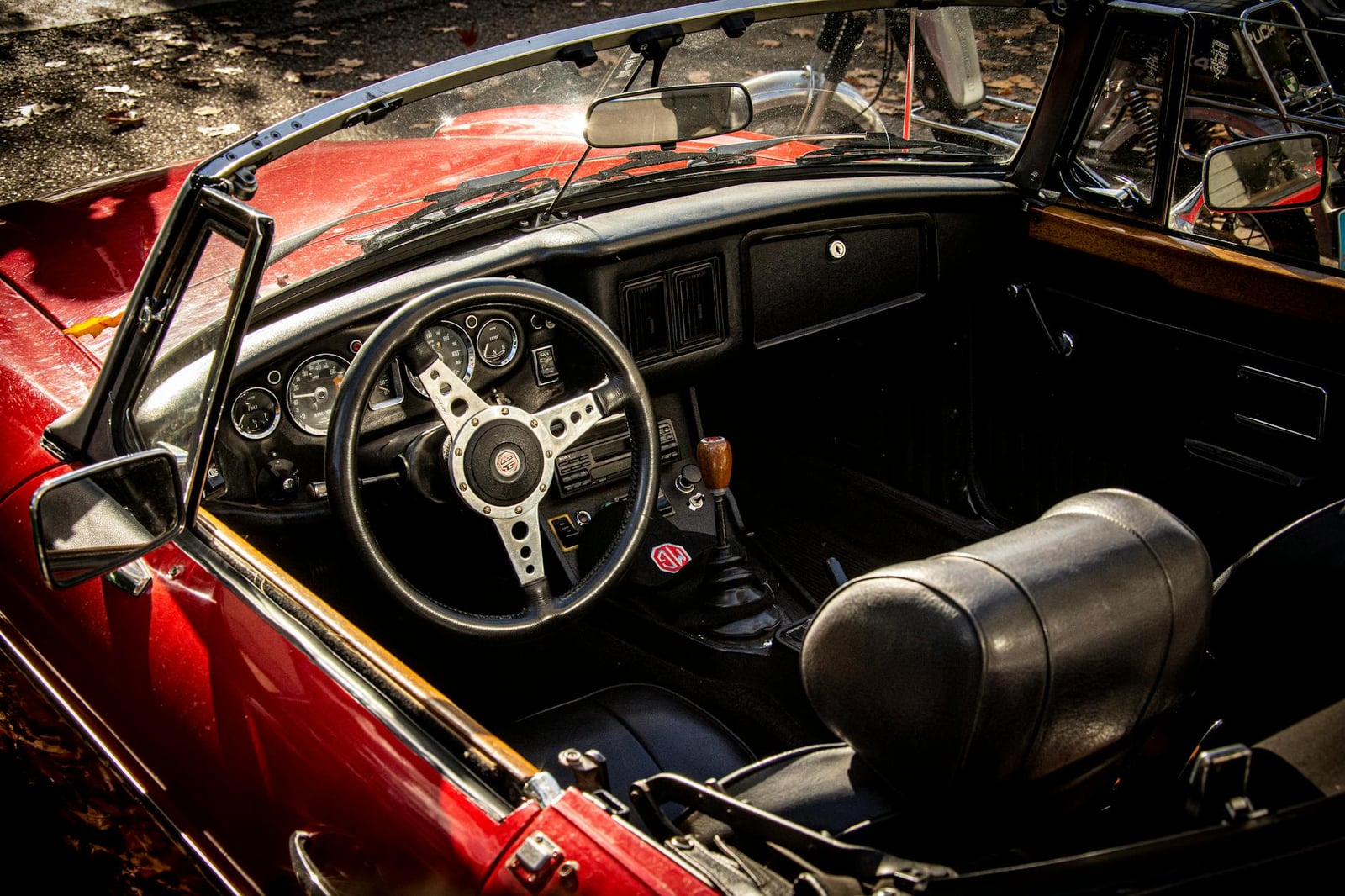The red interior of an MG MGB, showing the dashboard and steering wheel
