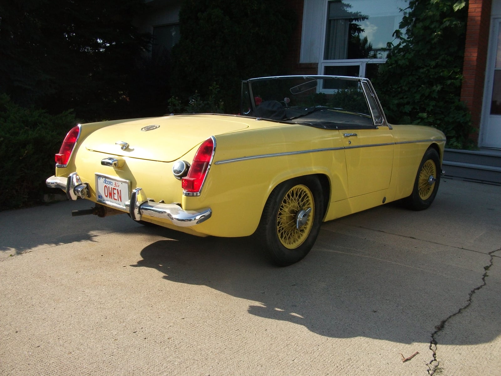 A yellow MG Midget with wire wheels, rear three-quarter view