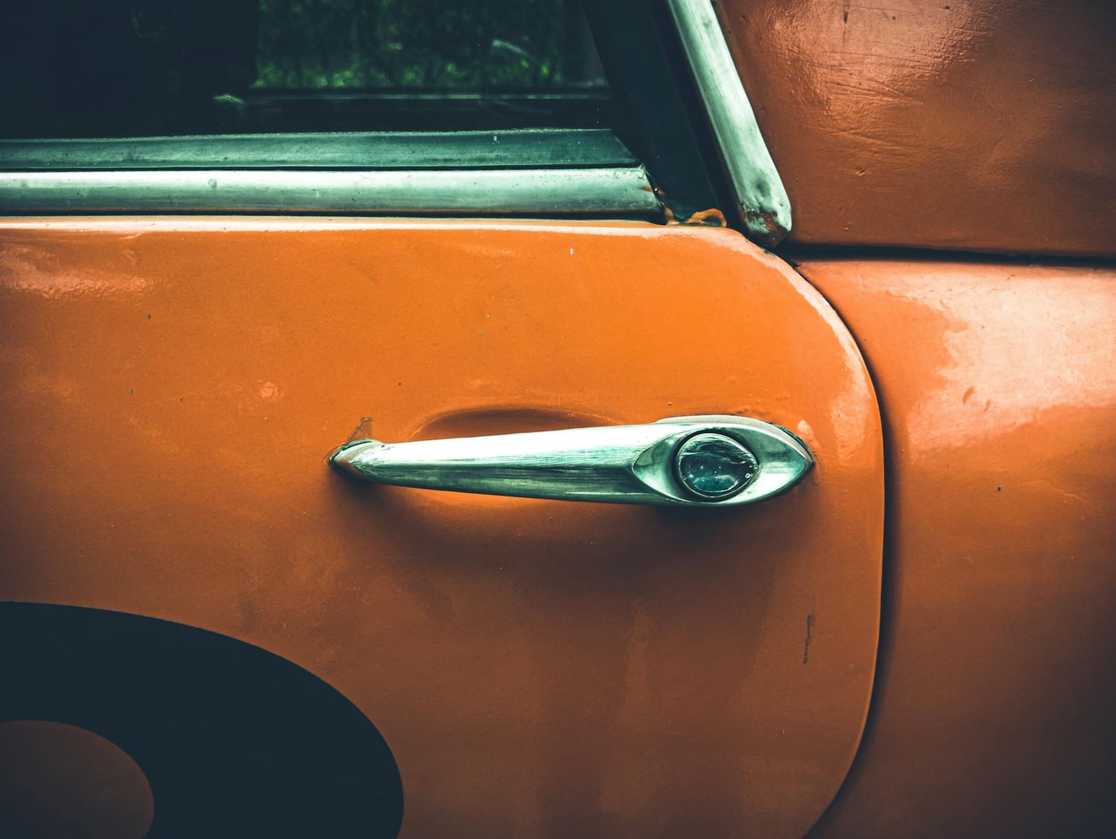 Close-up of the door and window seal of an orange MG Midget, showing some patina