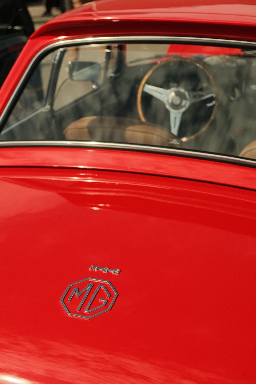 Close-up of the MG octagon badge on the rear quarter of a red MG MGB GT