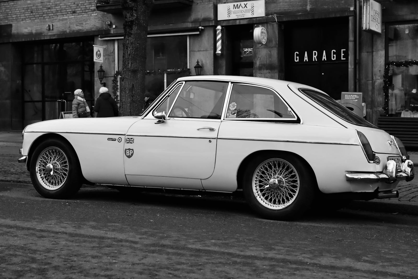 A white MG MGB GT in side profile, showing the fastback roofline, parked on a street