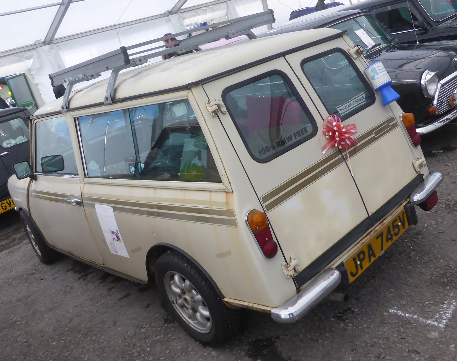 A cream Mini Clubman Estate at a show, rear three-quarter view