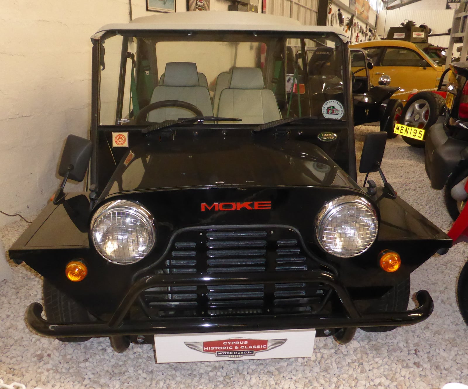 A black Mini Moke at an indoor show, front view