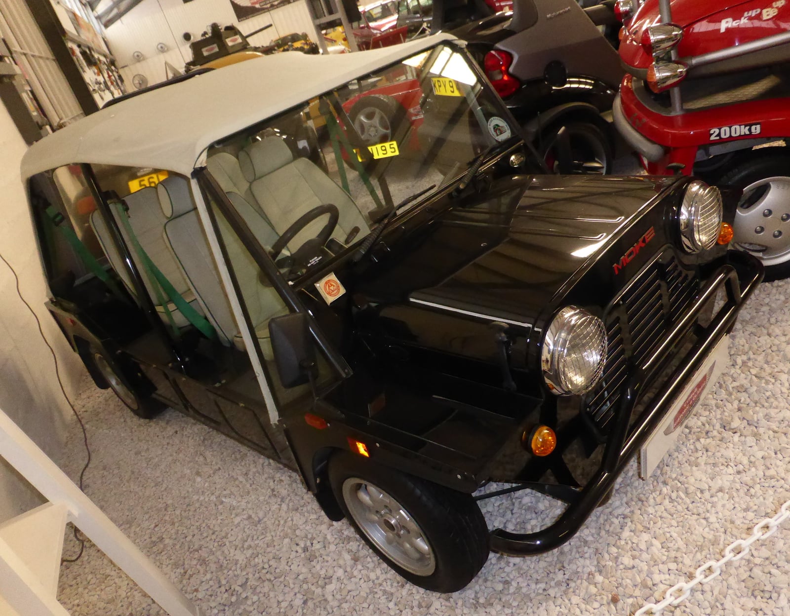 A black Mini Moke at an indoor show, front three-quarter view