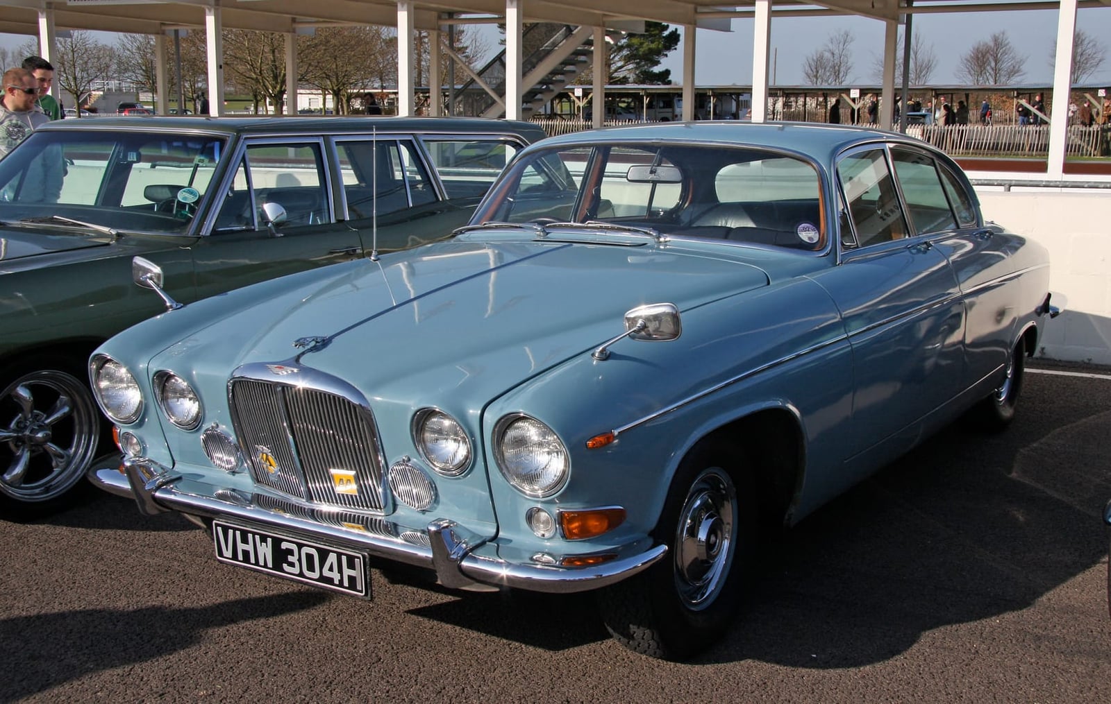 A pale blue Jaguar 420G parked on tarmac at a classic car event, front three-quarter view, UK registration VHW 304H