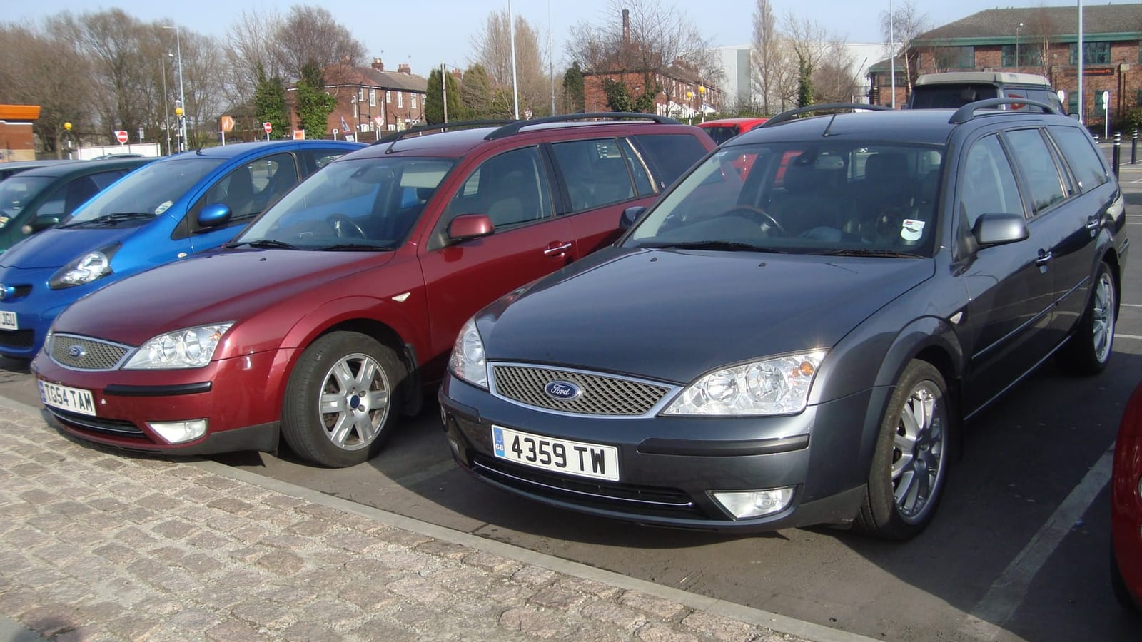 Two Mk3 Ford Mondeo estates, one grey and one red, parked side by side at a show in Britain