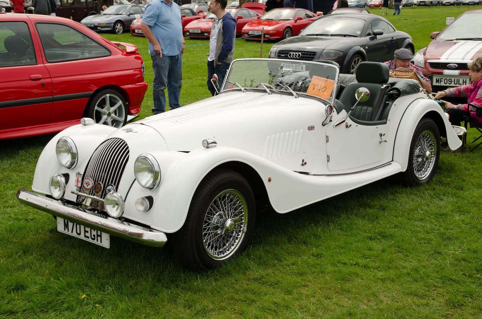 A white 2001 Morgan 4/4 1800 with wire wheels at a classic car show