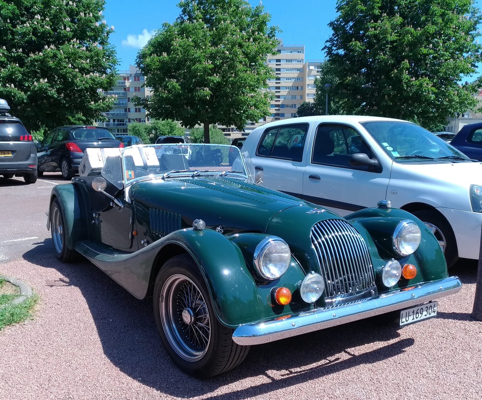 A maroon Morgan 4/4 being driven on a road, front view with the driver at the wheel, UK registration DWS 611