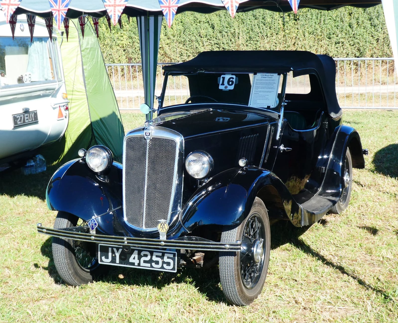 A dark blue Morris Eight two-seat tourer with its hood raised at an outdoor rally, UK registration JY 4255