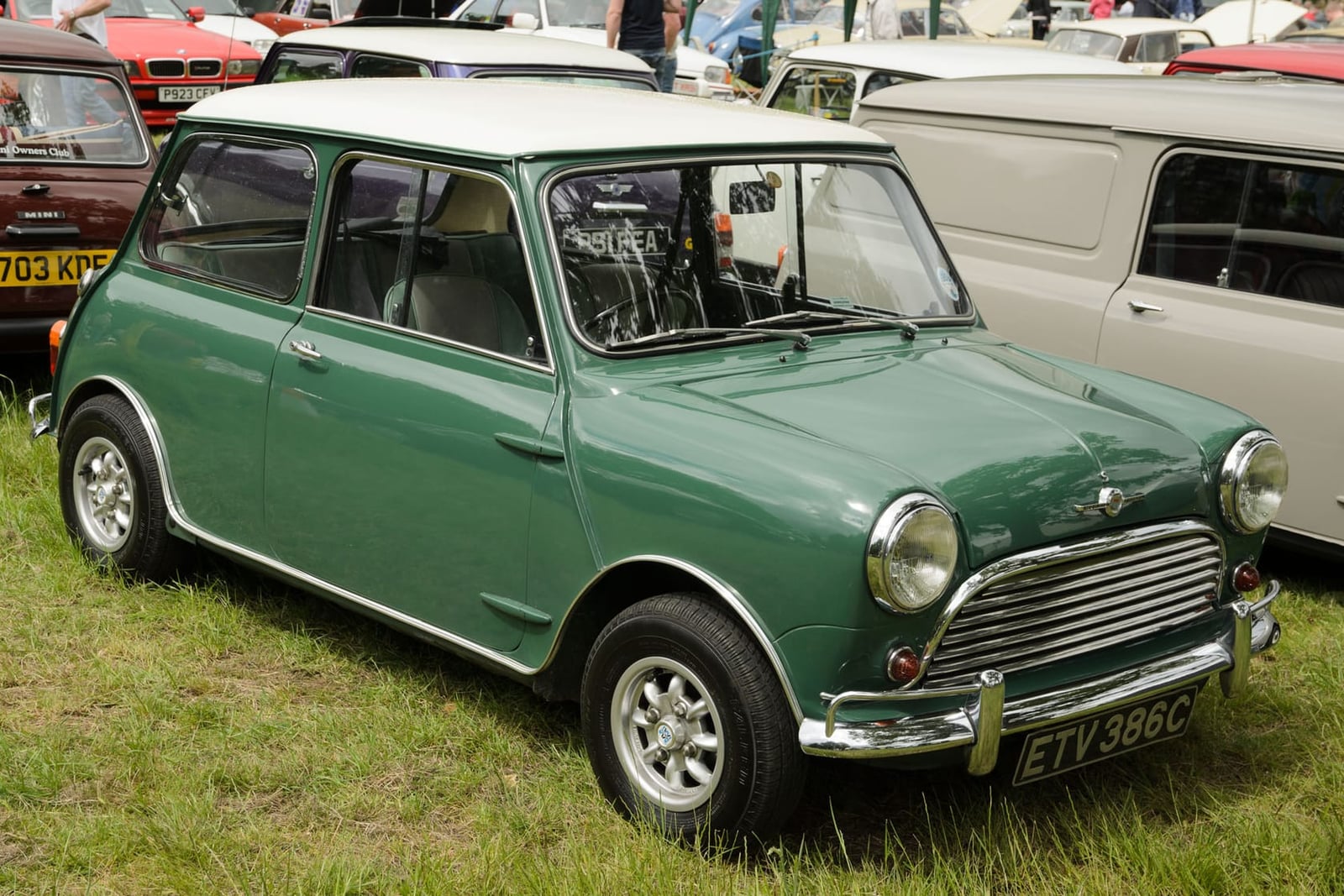 A green and white 1965 Morris Mini Cooper S 970 with a UK registration, parked on grass at a show