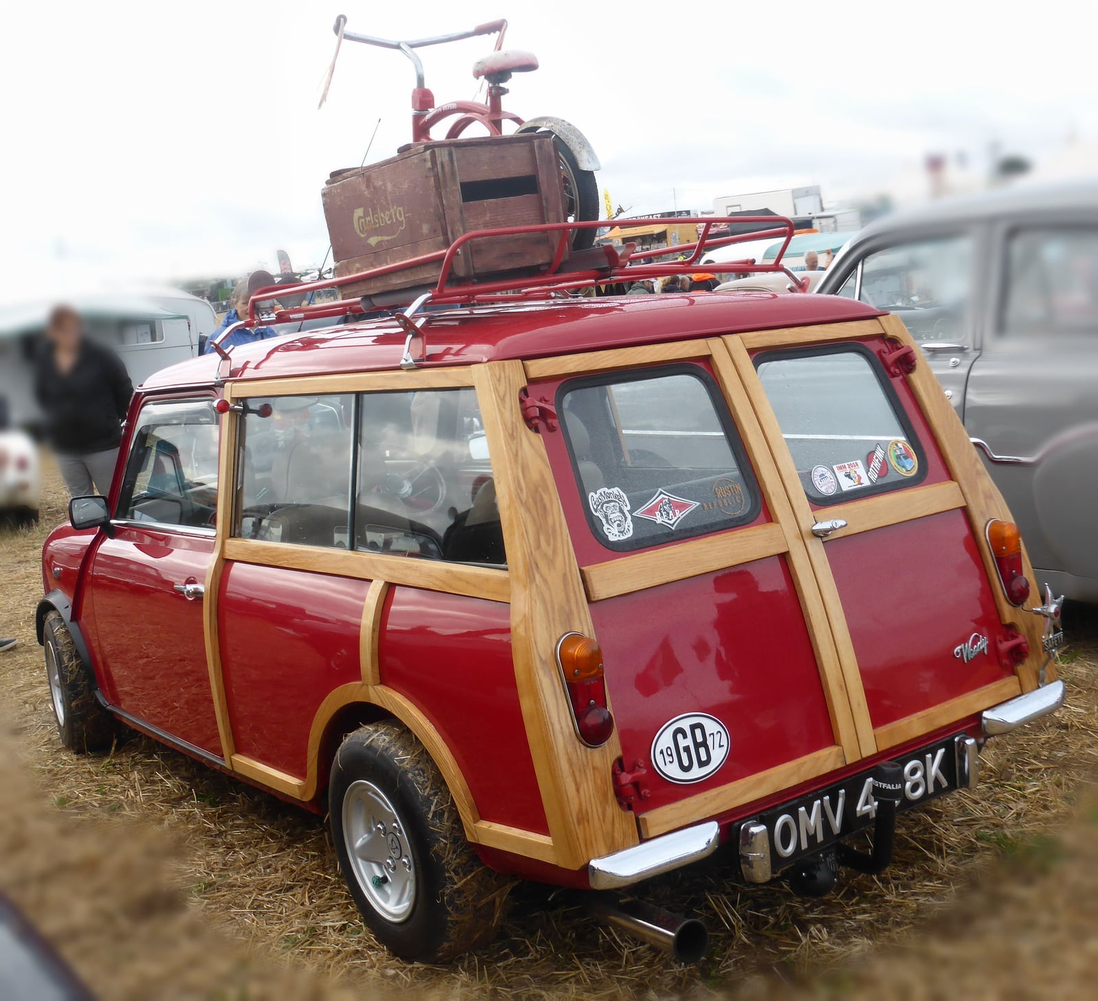 A red woody Mini Traveller at a show, rear three-quarter view