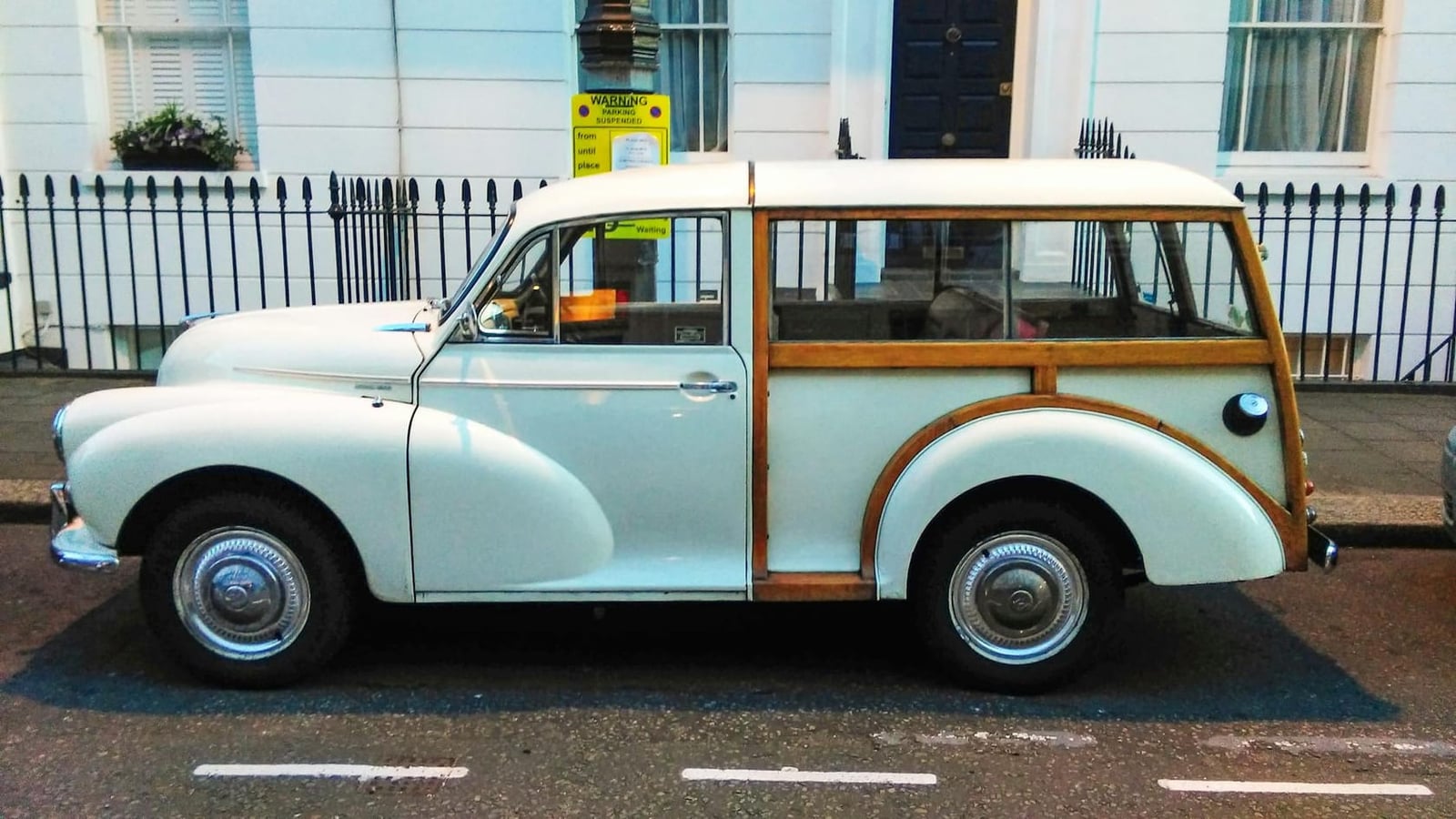 A white Morris Minor Traveller with varnished ash rear framing parked on a town street