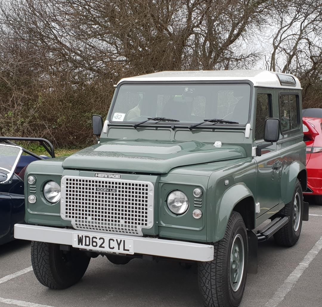 A grey-green Land Rover Defender 90 hard top rebuilt by a specialist in Heritage style, with a UK registration