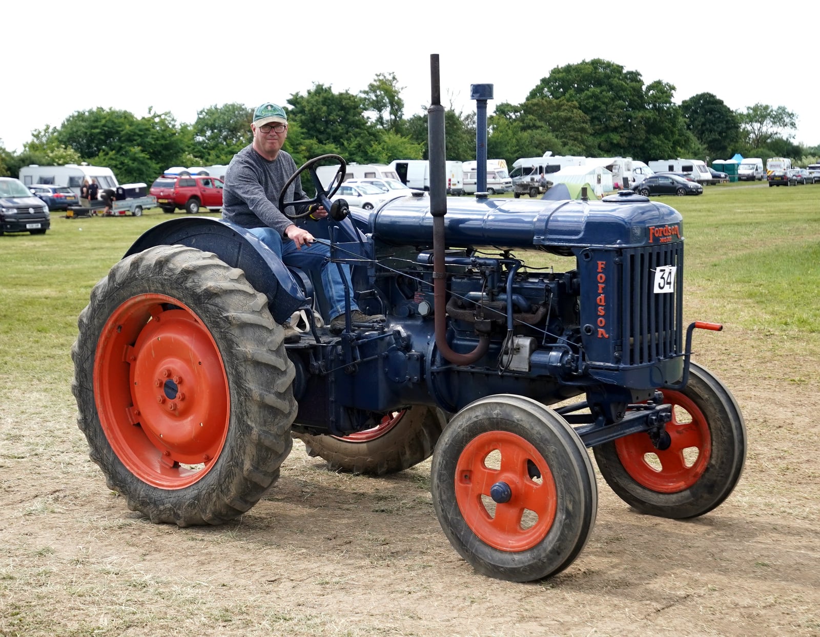 A blue 1945 Fordson E27N being driven at a vintage rally, a rider at the wheel
