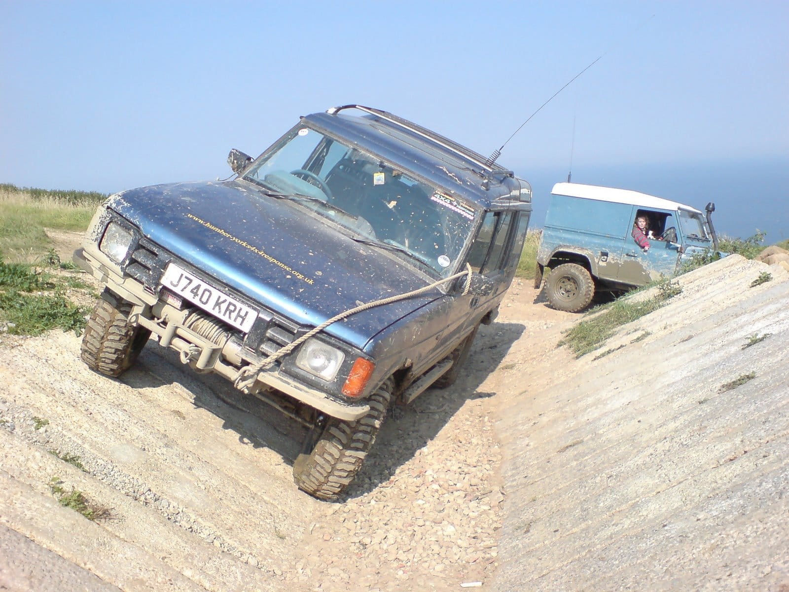A blue off-road-prepared Land Rover Discovery 200Tdi with a winch climbing a slope