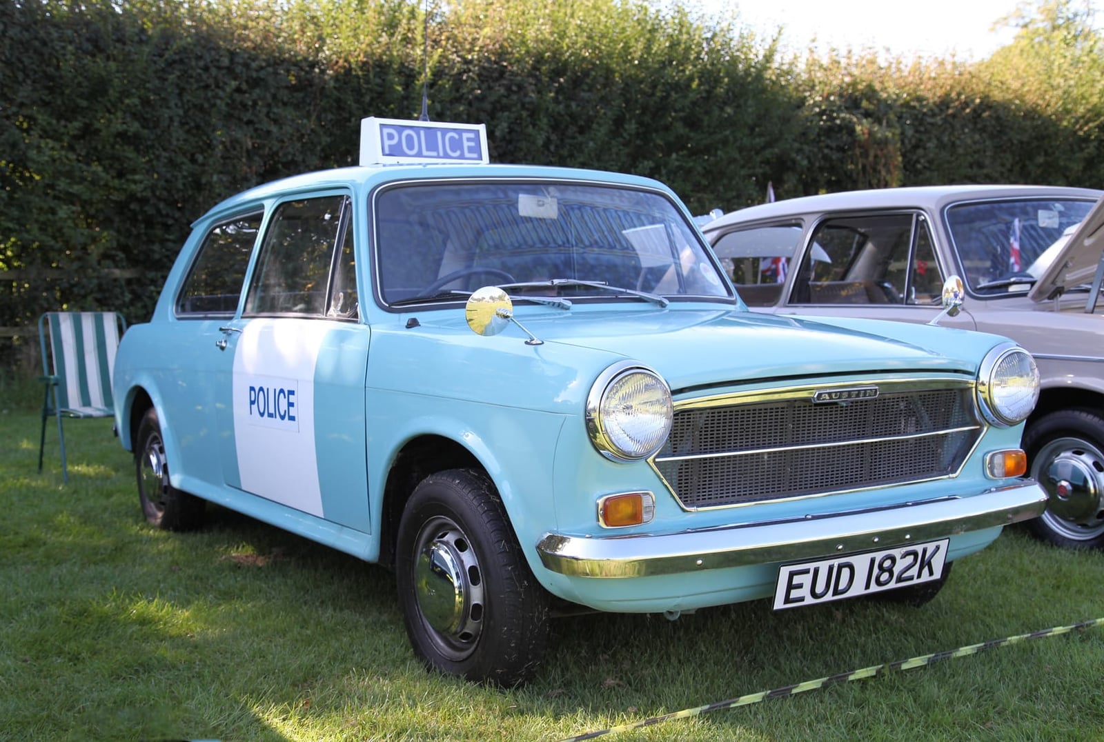 A pale blue and white 1971 Austin 1100 police panda car at a show, front three-quarter view
