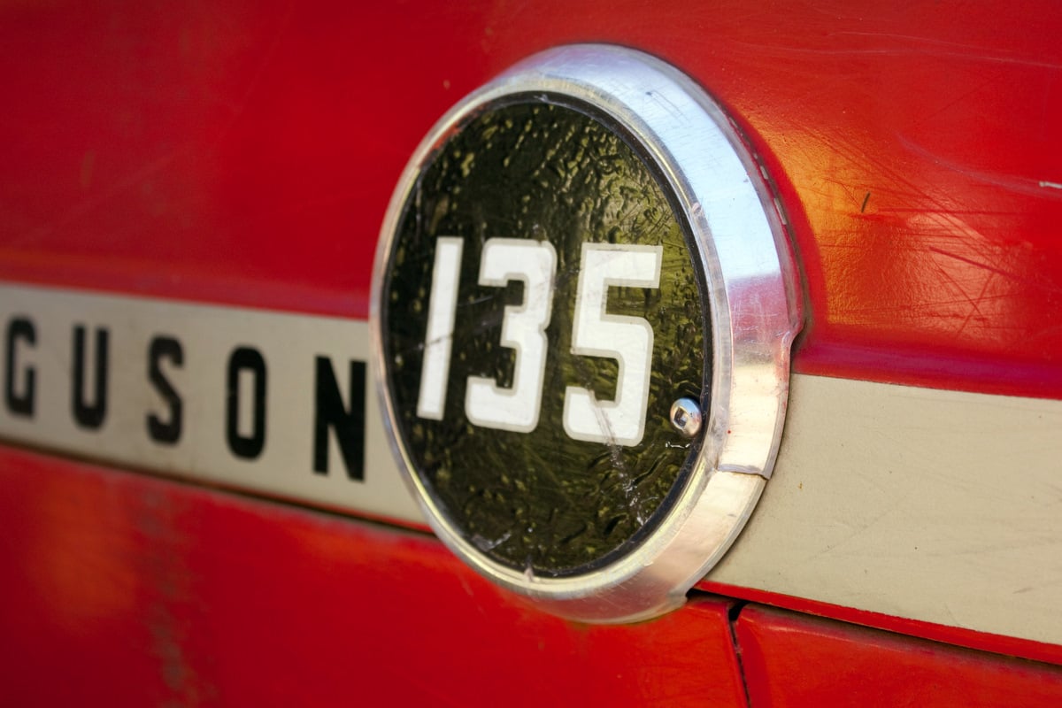 Close-up of the round 135 badge on the red bonnet of a Massey Ferguson tractor