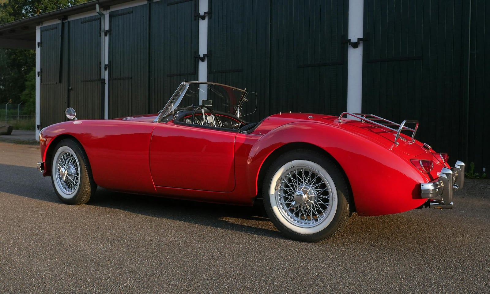 A red MG MGA roadster with wire wheels, rear three-quarter view