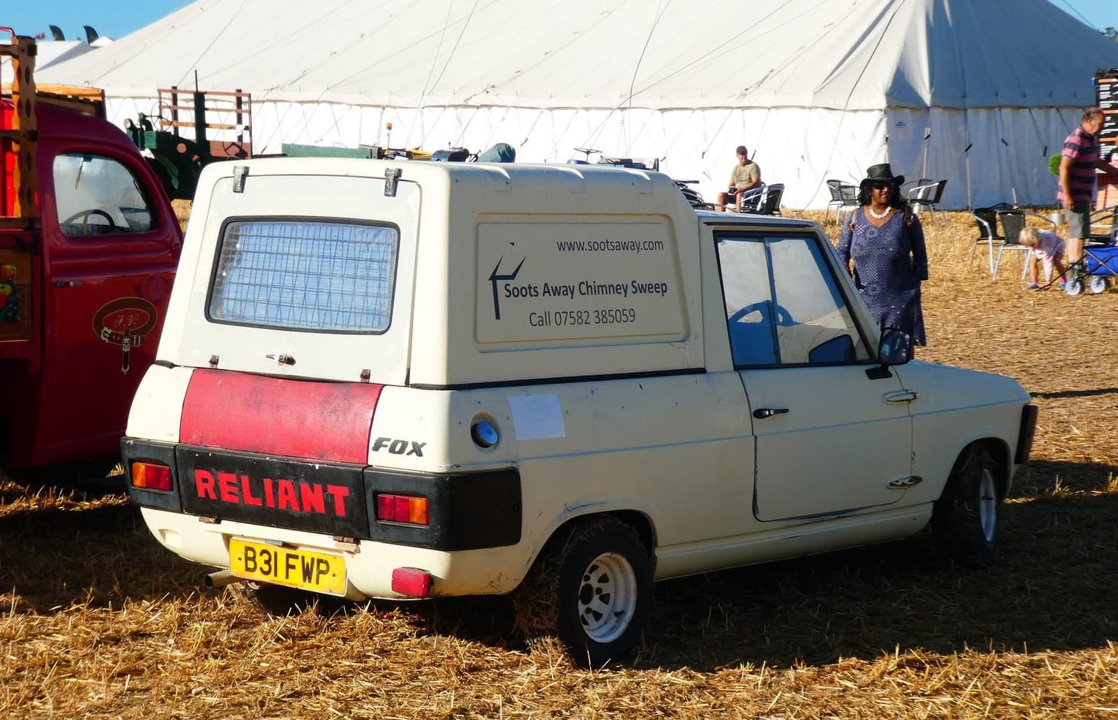 A cream Reliant Fox van in chimney-sweep signwriting at a vehicle show, rear three-quarter view, UK registration B31 FWP