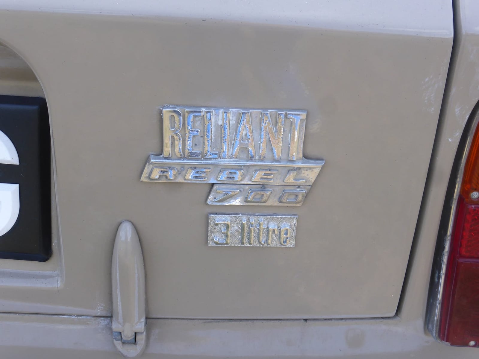 Close-up of the Reliant Rebel 700 badge and boot handle on a beige car