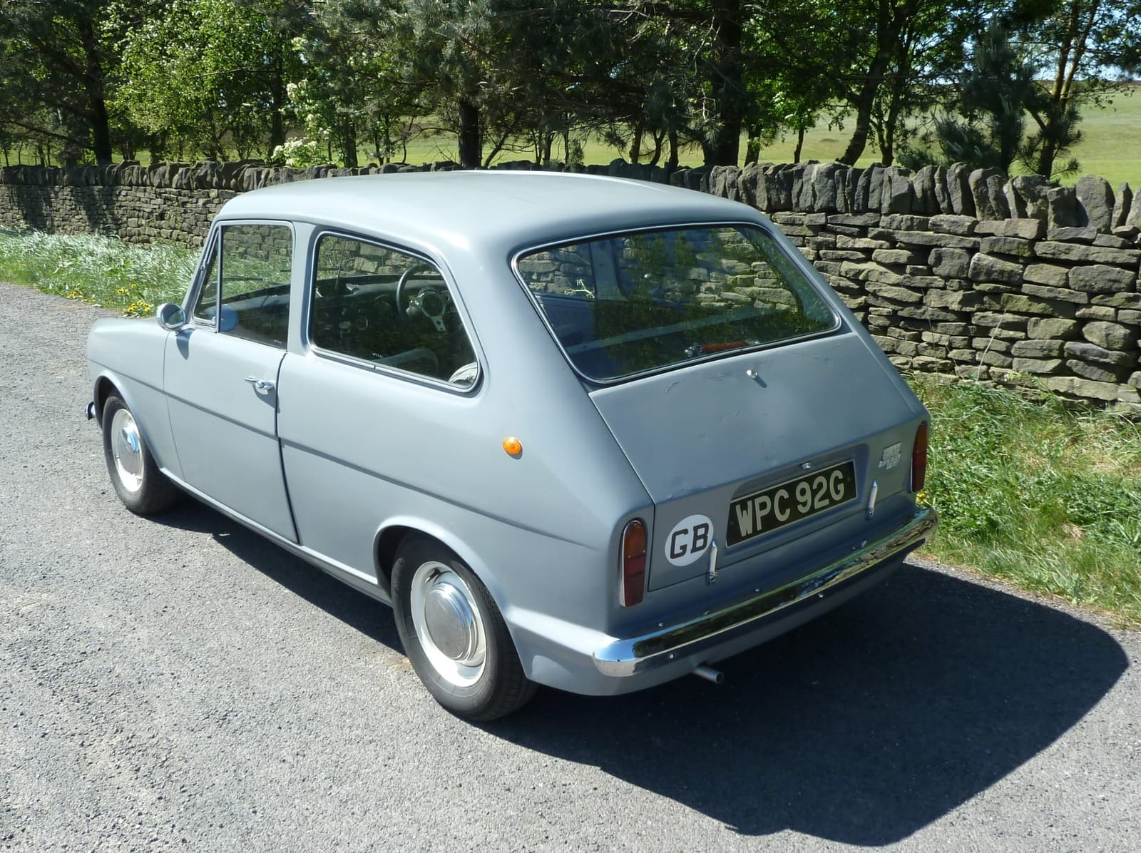 A grey 1969 Reliant Rebel 700 parked beside a dry stone wall, rear three-quarter view with a GB plate, UK registration WPC 92G