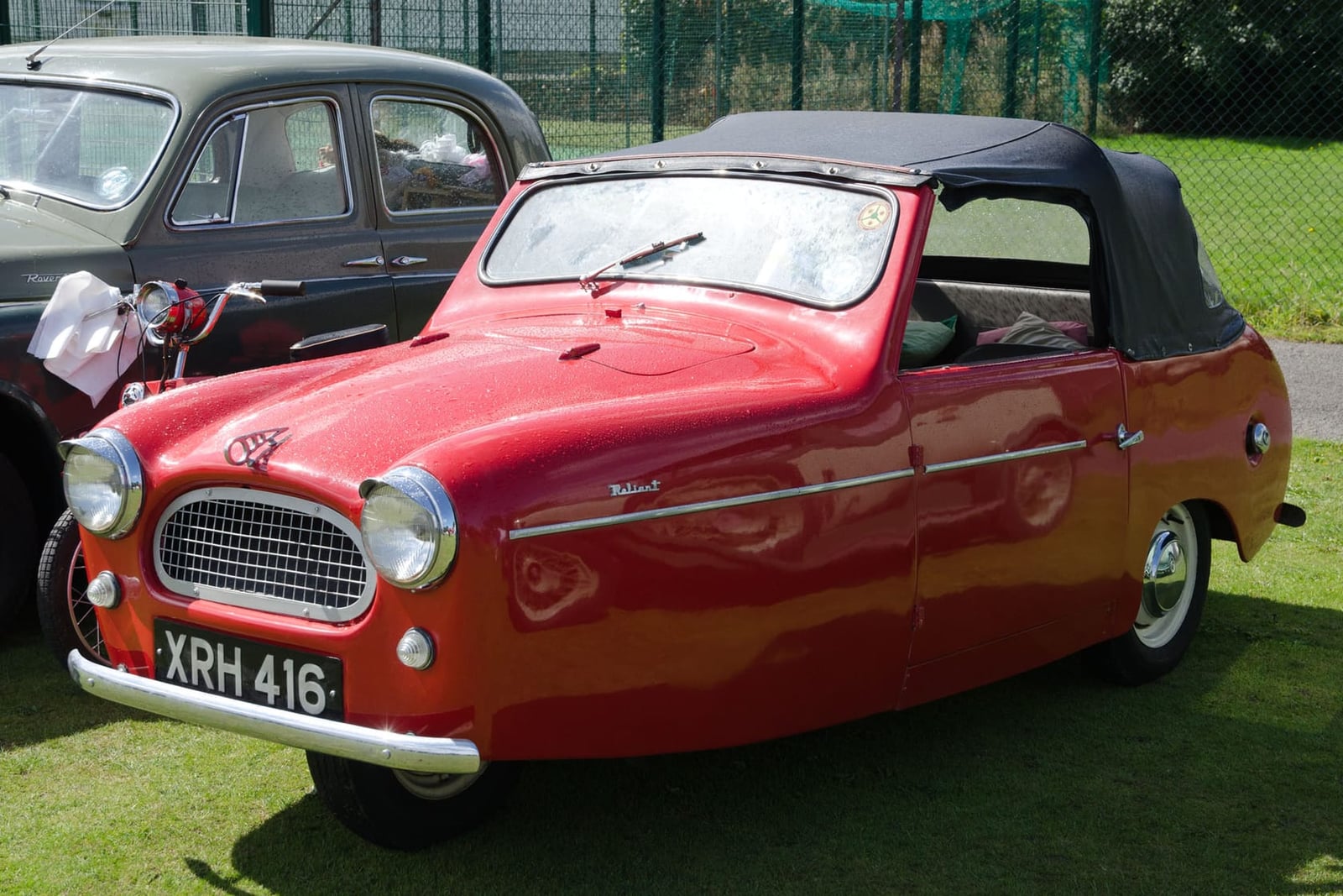 A red 1956 Reliant Regal Mk 3 convertible at a show, front three-quarter view, UK registration XRH 416