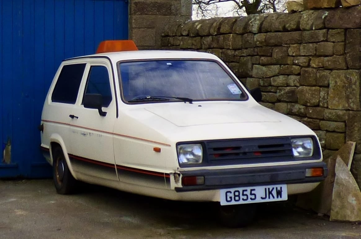 A white Reliant Rialto parked beside a stone wall, front three-quarter view, UK registration G855 JKW
