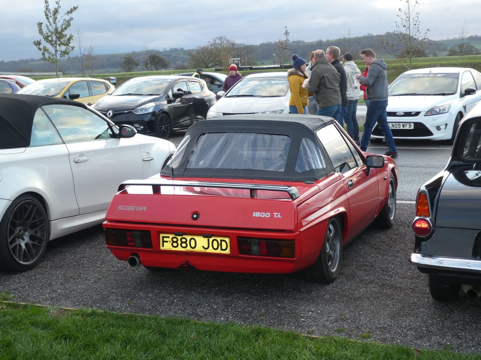 A red Reliant Scimitar 1800Ti parked at a car meet, rear three-quarter view, UK registration F880 JOD