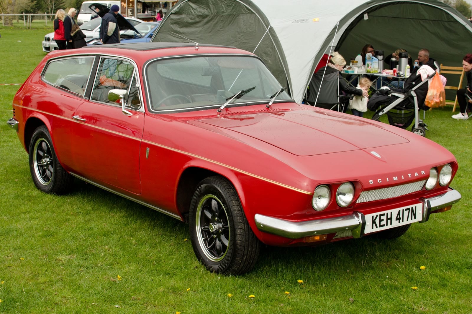 A red Reliant Scimitar GTE parked on grass at a classic vehicle show, front three-quarter view, UK registration KEH 417N