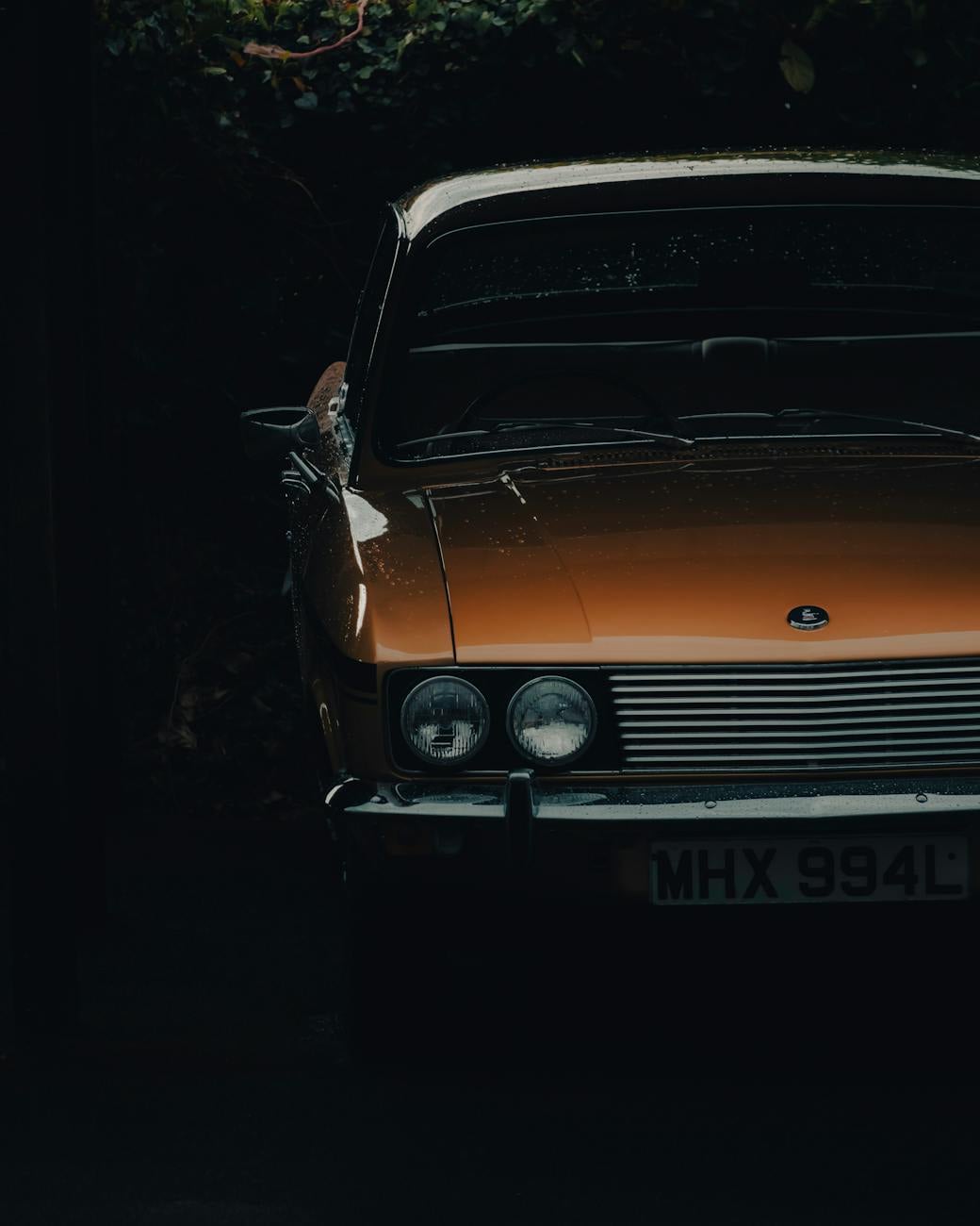 The front of an orange Reliant Scimitar GTE in low light, UK registration MHX 994L